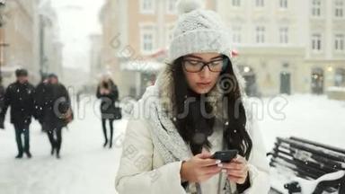 美丽的女人穿着冬衣，微笑着，一边用手机<strong>发信息</strong>